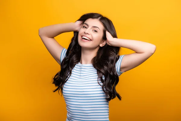 Morena Mujer Endureciendo Pelo Largo Rizado Sonriendo Aislado Amarillo — Foto de Stock