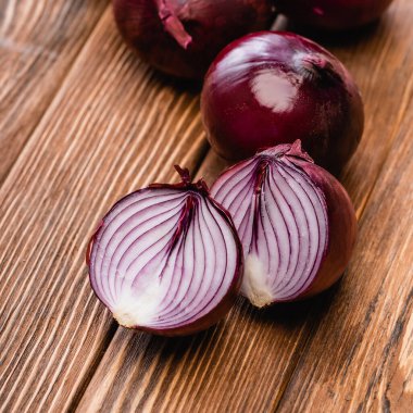 close up view of red onion halves on wooden table clipart