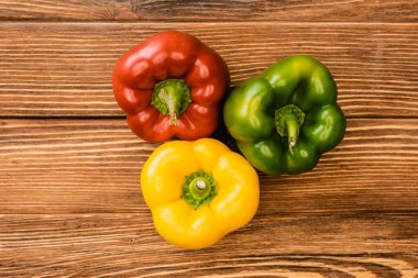 top view of colorful ripe bell peppers on wooden table clipart