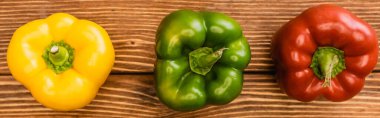 top view of colorful ripe bell peppers on wooden table, panoramic shot clipart