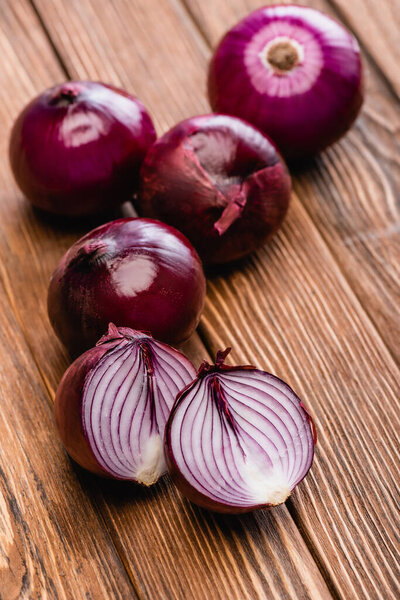 cut and whole red onion on wooden table