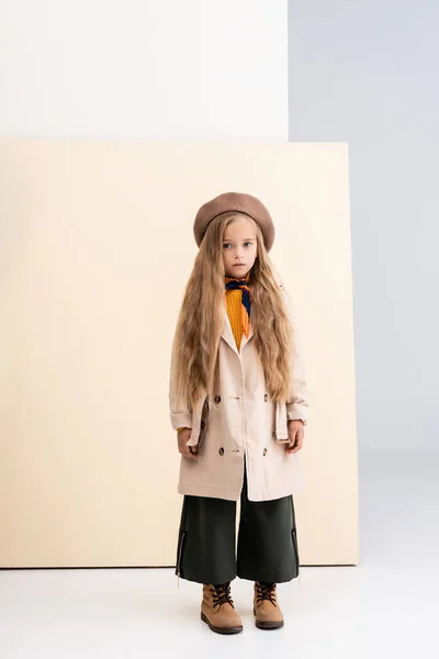 ファッショナブルなブロンド女の子で秋服上のベージュと白の背景 — ストック写真