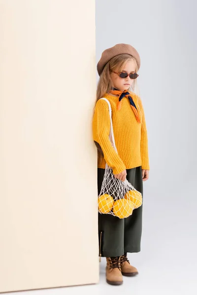 선글라스를 베이지 배경에 가방을 포즈를 취하는 — 스톡 사진
