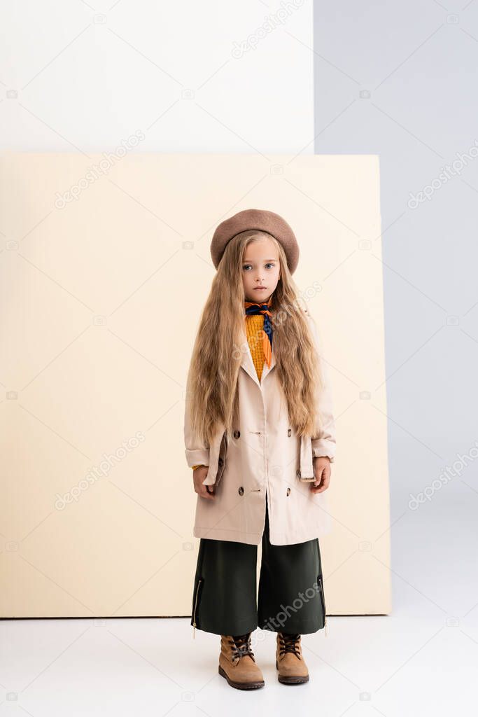 fashionable blonde girl in autumn outfit on beige and white background