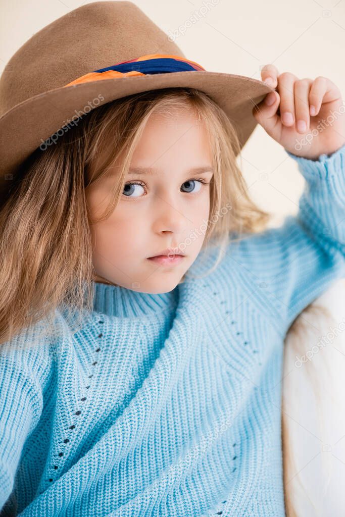 fashionable blonde girl in brown hat and blue sweater