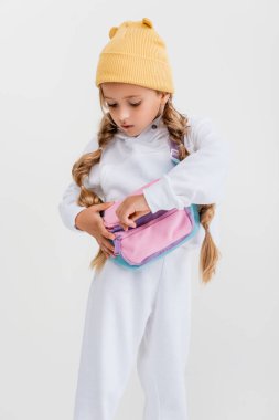 blonde girl in sportswear unfastening belt bag isolated on white clipart