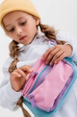 Spor kıyafetleri içindeki sarışın kızın seçici odak noktası beyaz kemer çantasına izole edilmiş.