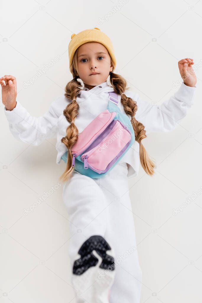 selective focus of blonde girl in sportswear posing on white background