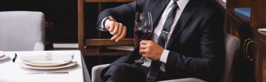 Website header of man in suit holding glass of wine and checking time in restaurant  clipart