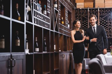 Seçici odak noktası, restoranda yürürken zarif erkek arkadaşının eline dokunan genç bir kadın. 