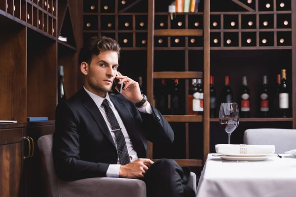 Foco Seletivo Homem Terno Falando Smartphone Perto Copo Vinho Mesa — Fotografia de Stock