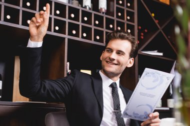 Seçici odak noktası, takım elbiseli, elini kaldırmış restoranda gözlerini kaçıran adam.