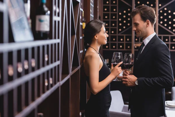 レストランでワインのグラスを保持しながら お互いを見てエレガントなカップルの選択的な焦点 — ストック写真