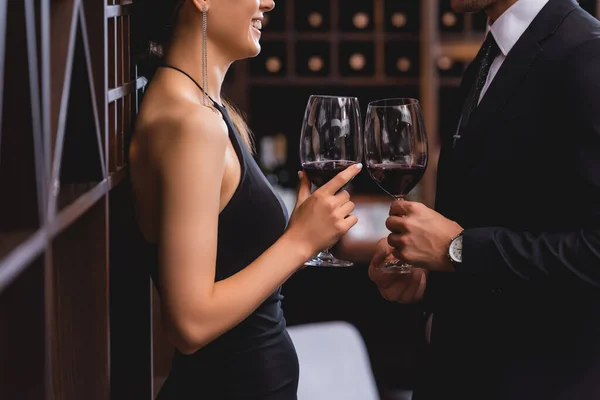 レストランでスーツでボーイフレンドの近くにワインのガラスを保持しているエレガントな女性の作物ビュー — ストック写真