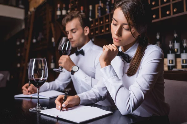 Selective Focus Concentrated Sommelier Writing Notebook Colleague Glass Wine — Stock Photo, Image