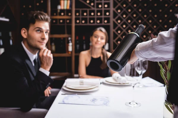 Вибірковий Фокус Сомельє Тримає Пляшку Вина Біля Елегантної Пари Ресторані — стокове фото