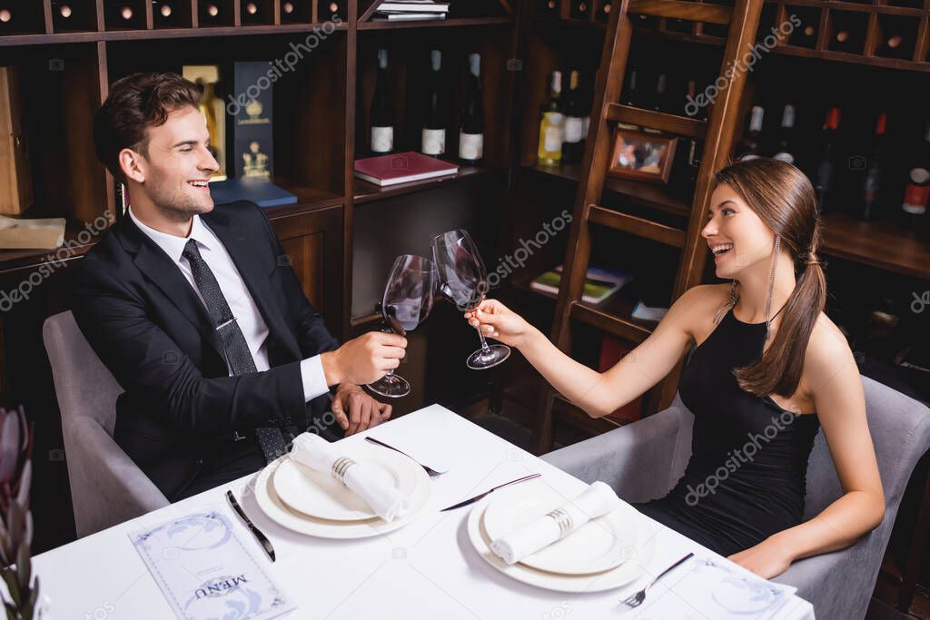 Selective focus of elegant couple toasting with glasses of wine at table in restaurant 