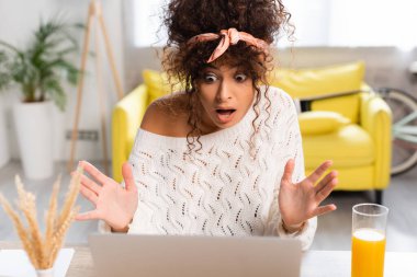 Bir bardak portakal suyunun yanındaki dizüstü bilgisayara bakan şaşkın serbest çalışanın seçici odağı.