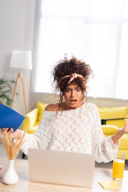 Dizüstü bilgisayara bakıp not defteri tutan şoke olmuş serbest çalışanın seçici odak noktası