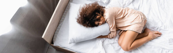 panoramic concept of barefoot woman with closed eyes hugging pillow while sleeping on bed