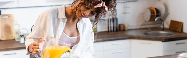 Panoramic Crop Curly Joyful Woman Holding Jug Pouring Fresh Orange — Stock Photo, Image