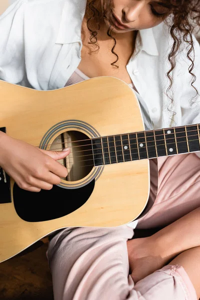 곱슬머리 여자가 집에서 어쿠스틱 기타를 — 스톡 사진