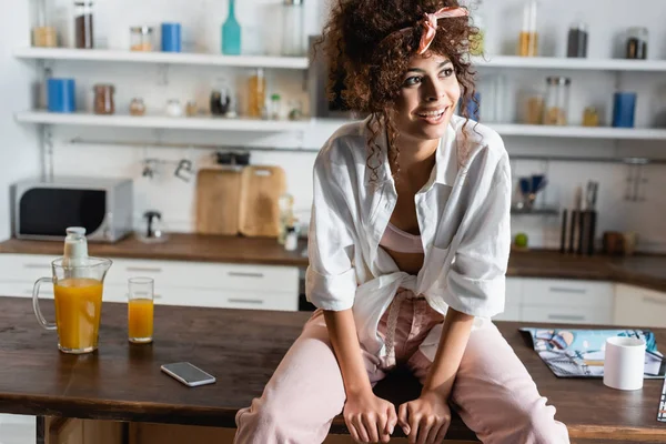 Femme Bouclée Assis Sur Table Regardant Loin Dans Cuisine — Photo