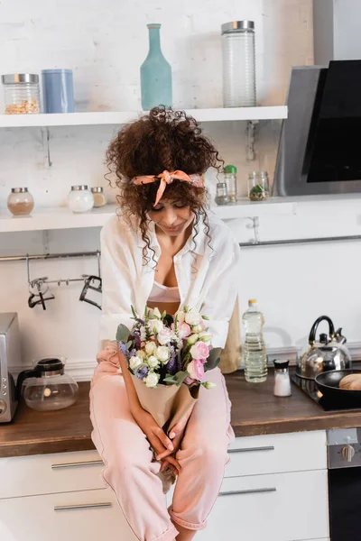 Curly Woman Sitting Kitchen Table Looking Flowers — Stock Photo, Image