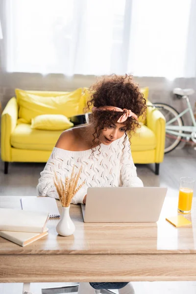 Skupiony Freelancer Patrząc Laptopa Pobliżu Szklanki Soku Pomarańczowego — Zdjęcie stockowe