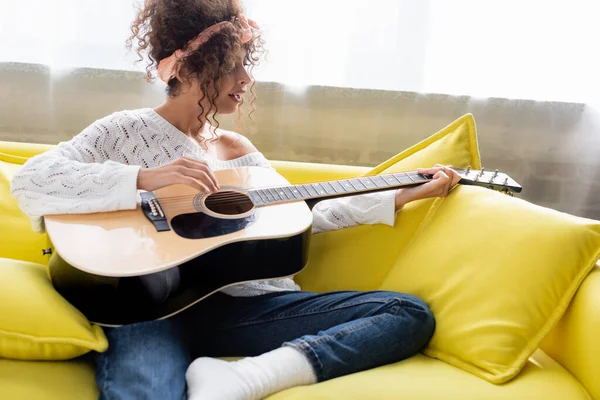 Kıvırcık Kadın Akustik Gitar Çalıyor Oturma Odasında Şarkı Söylüyor — Stok fotoğraf