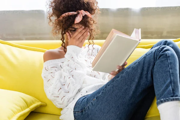 Upset Young Woman Reading Book Covering Face Living Room — Stock Photo, Image