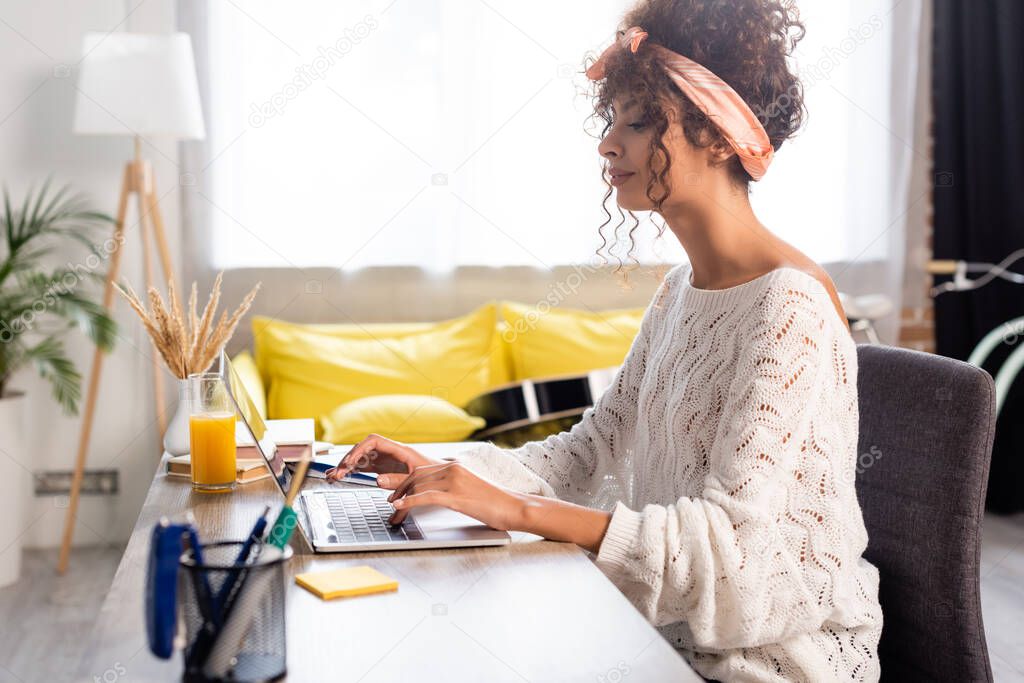 profile of focused freelancer using laptop while working from hone