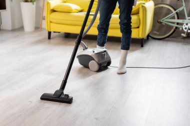 Evi temizlerken elektrikli süpürge kullanan çoraplı kadın görüntüsü