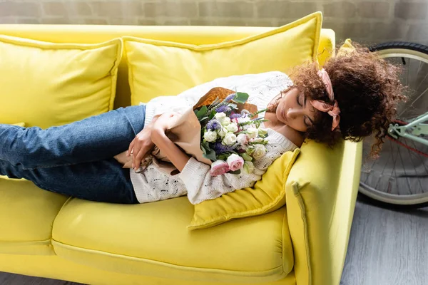 Young Curly Woman Closed Eyes Lying Yellow Sofa Flowers — Stock Photo, Image