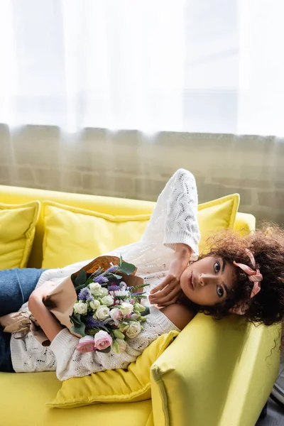Young Curly Woman Lying Yellow Sofa Flowers — Stock Photo, Image