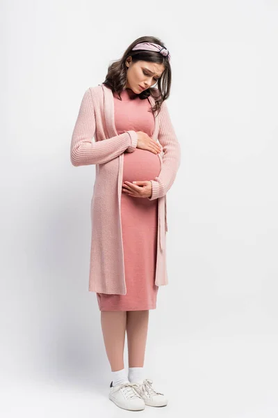 头带的孕妇在白色抽筋的情况下摸着肚子 — 图库照片