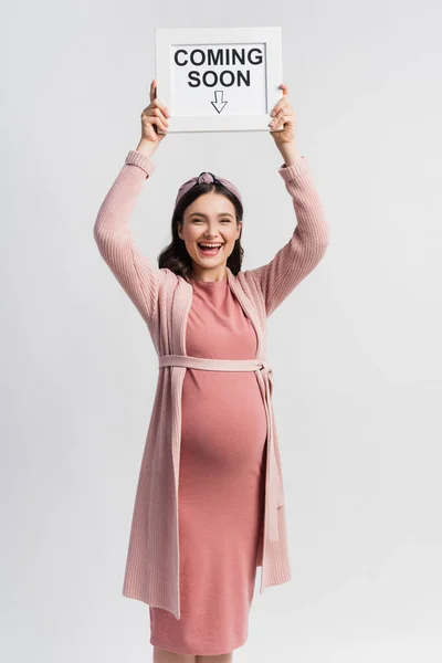 Opgewonden Zwanger Vrouw Holding Board Met Coming Soon Belettering Geïsoleerd — Stockfoto