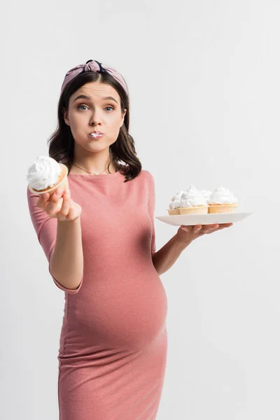 Femme Enceinte Tenant Plaque Tout Mangeant Cupcake Isolé Sur Blanc — Photo