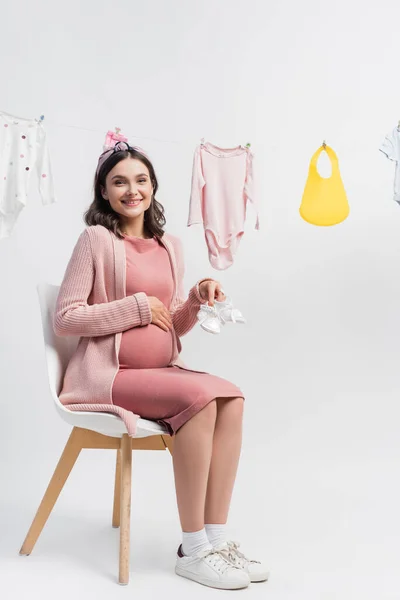 Young Pregnant Woman Holding Tiny Boots Sitting Baby Clothes Clothing — Stock Photo, Image