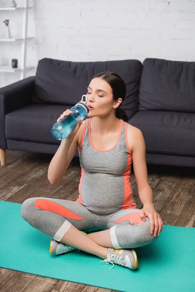 Mujer Embarazada Sosteniendo Botella Deporte Mientras Bebe Agua Sienta Alfombra — Foto de Stock