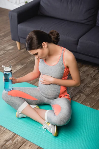 Mujer Embarazada Tocando Vientre Sosteniendo Botella Deportes Sentado Alfombra Fitness — Foto de Stock