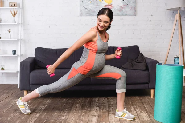 自宅でピンクのダンベルで運動する楽しい妊婦 — ストック写真