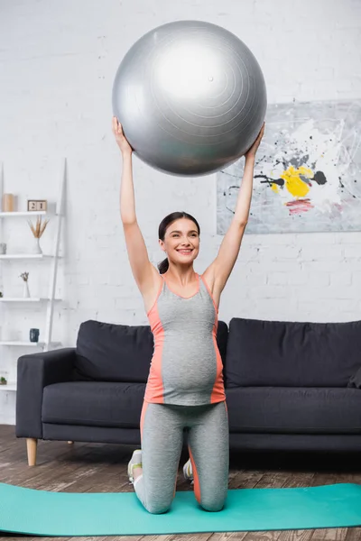 リビングルームでフィットネスボールで働く喜びと妊娠中の女性 — ストック写真