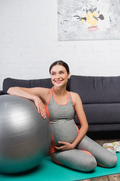 Radostná Těhotná Žena Dotýkající Břicha Při Sezení Blízkosti Fitness Míč — Stock fotografie