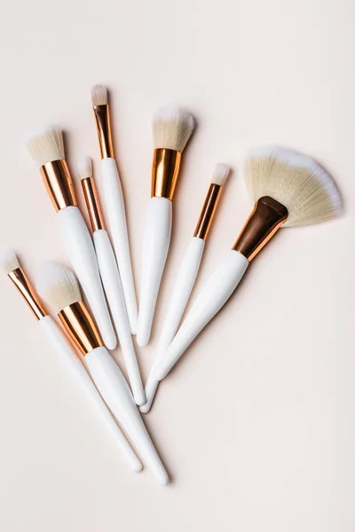 Top view of white and golden cosmetic brushes set on beige background — Stock Image Top View White Golden Cosmetic Brushes Set Beige Background Stock Picture