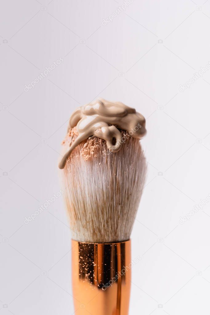 close up view of cosmetic brush with face powder and foundation isolated on white