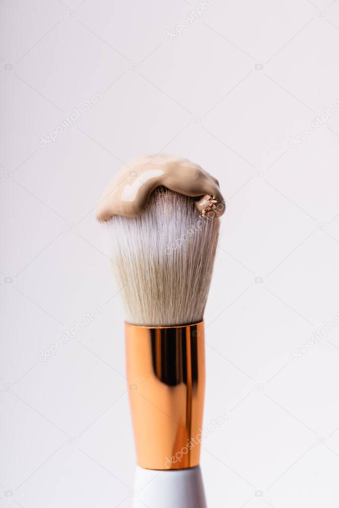 close up view of cosmetic brush with face foundation isolated on white