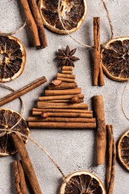 Gri arkaplanda anason yıldızı olan çam ağacından yapılmış tarçın çubuklarının üst görüntüsü