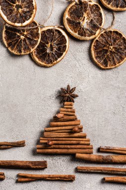Gri arkaplanda anason yıldızı olan çam ağacından yapılmış tarçın çubuklarının üst görüntüsü