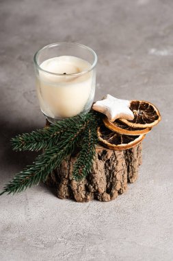 Çam brunch 'lı kokulu mum, kurutulmuş portakal dilimleri ve ahşap tezgahta kurabiye.